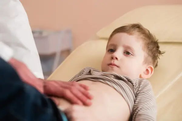 Un bambino viene visitato per sospetto neuroblastoma. Il medico gli tocca delicatamente l'addome.